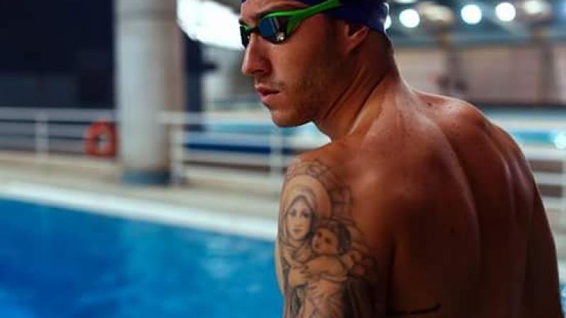 male swimmer poses at the side of the pool