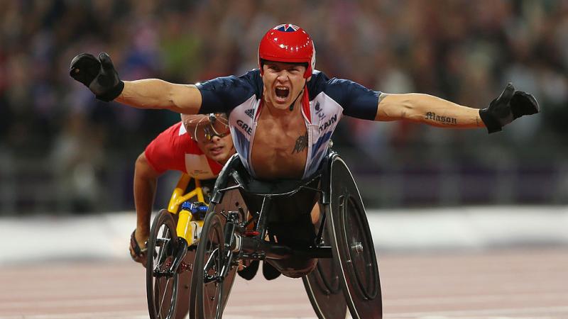 Wheelchair racer celebrates crossing finish line