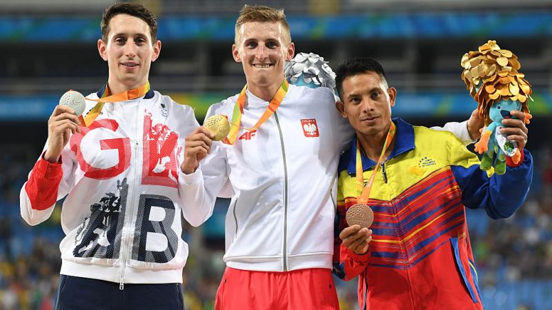 three men with medals on the podium