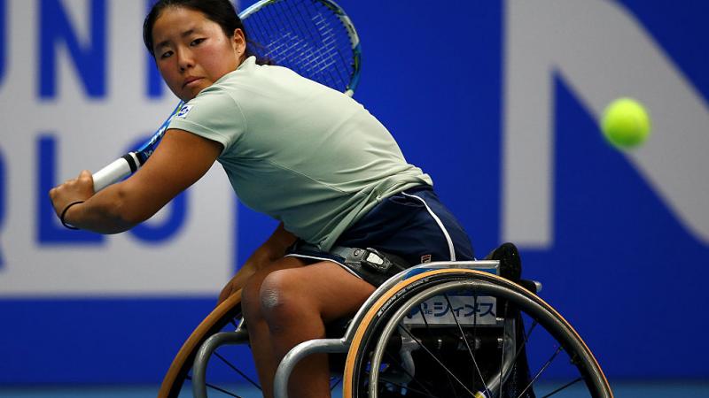 female wheelchair tennis player hits a backhand