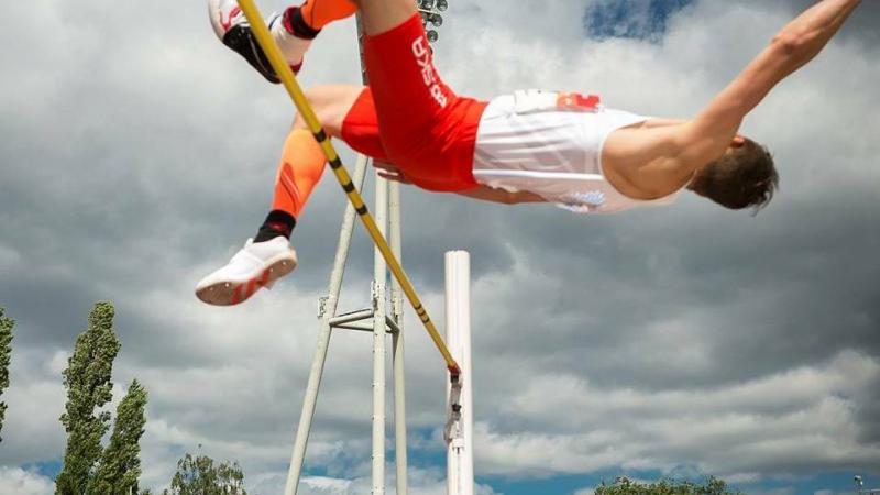 man jumps horizontally over high jump bar