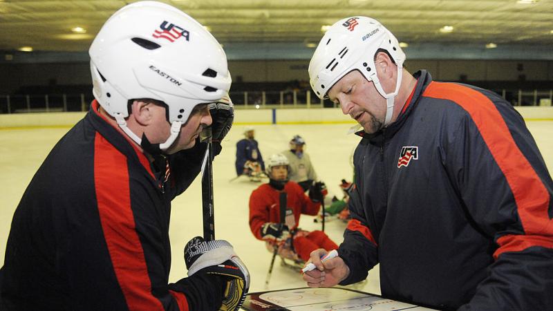 two men discuss ice hockey tactics on a tactics board