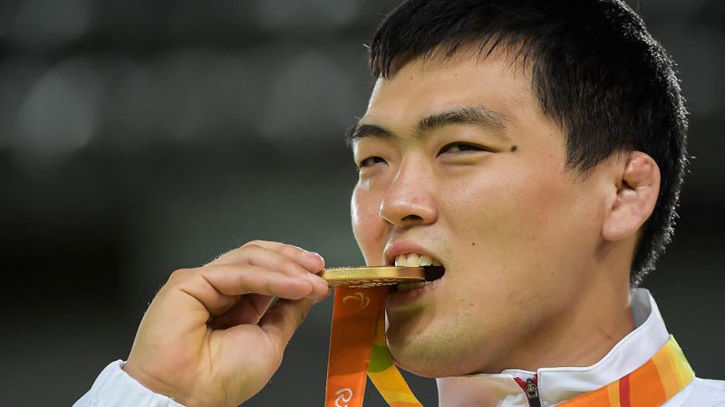 man bites gold medal in celebration 