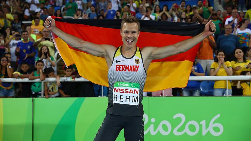 Man holds up German flag and smiles