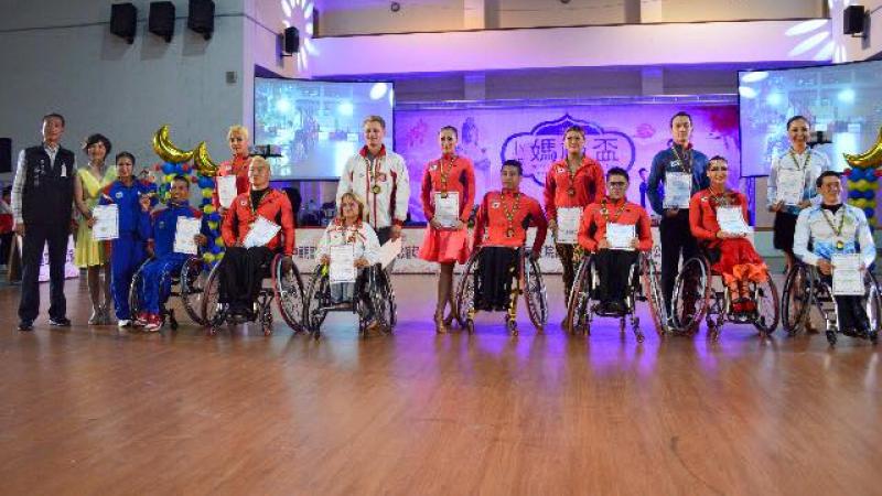 A row of men and women in wheelchairs with competition certificates