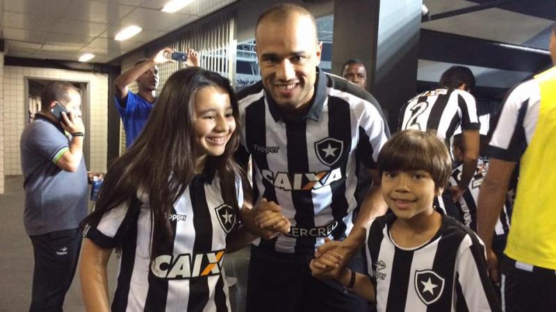 A footballer hugs his son and daughter before a game