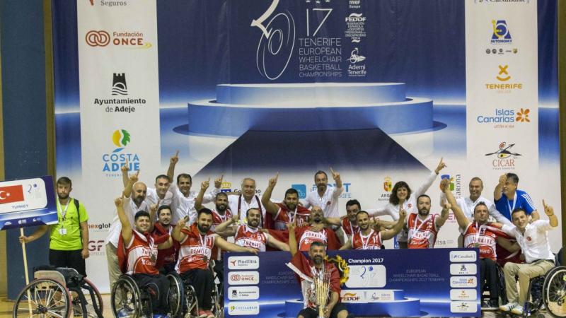 a group of men in wheelchairs celebrate with their trophy