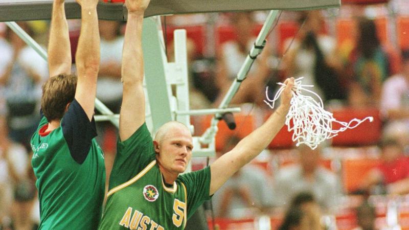 A man hangs off a basketball hoop