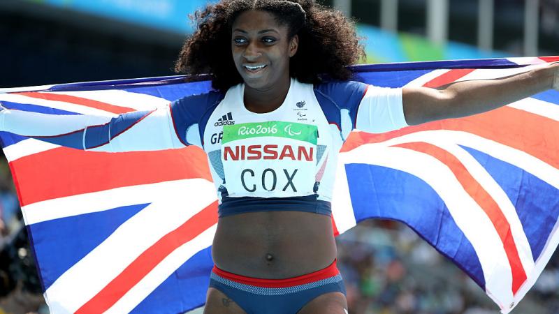 a female para athlete holds up a British flag