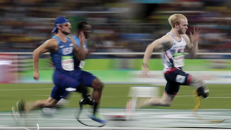 three para sprinters run towards the finish line