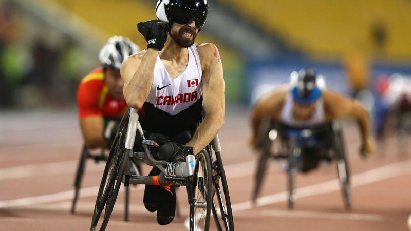 a wheelchair racer pumps his fist after crossing the line