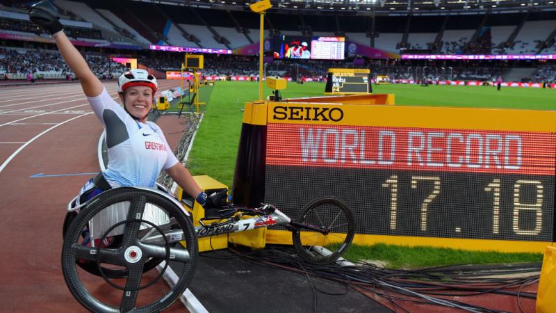 Woman in racing wheelchair next to a screen