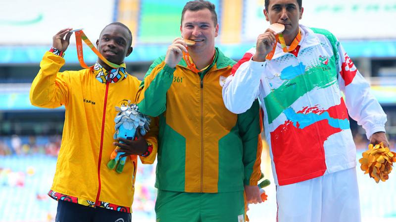 three men stand on a podium with their medals