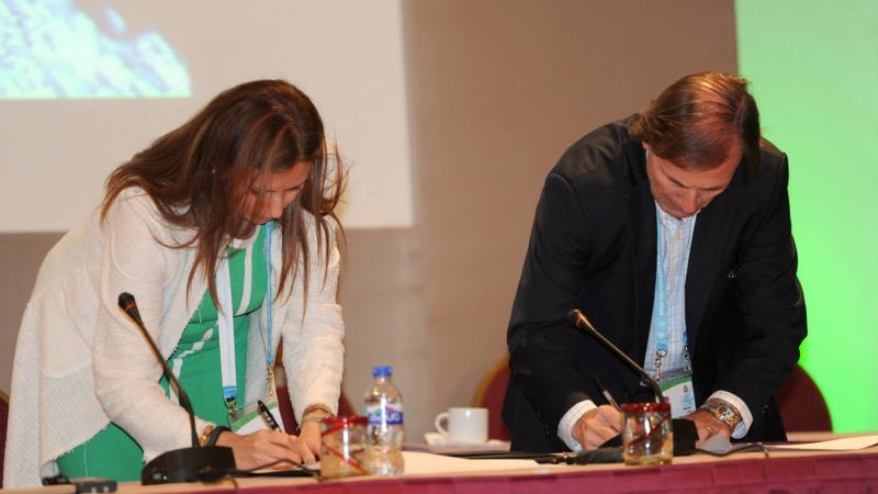 a man and a woman sign documents on a table