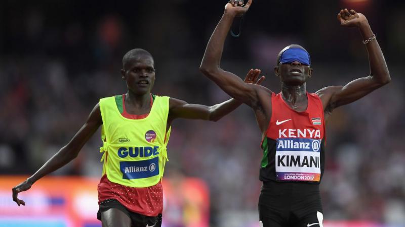 a blindfolded runner and his guide celebrate after crossing the finish line 