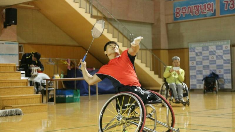 a para badminton player in a wheelchair goes for a shot