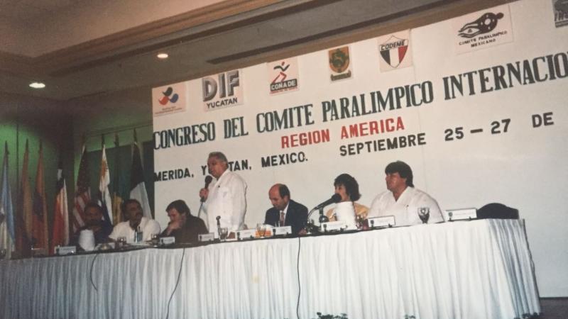a group of men speak at a table