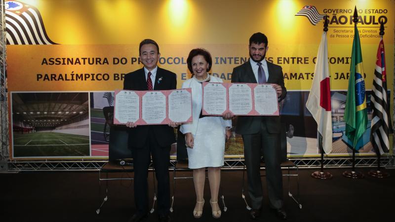 two men and a woman stand and smile for the camera