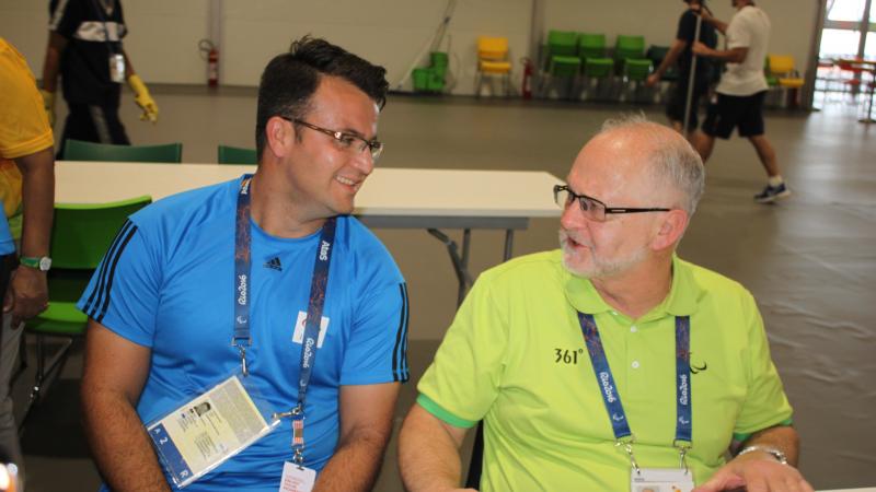 two men chat at a table