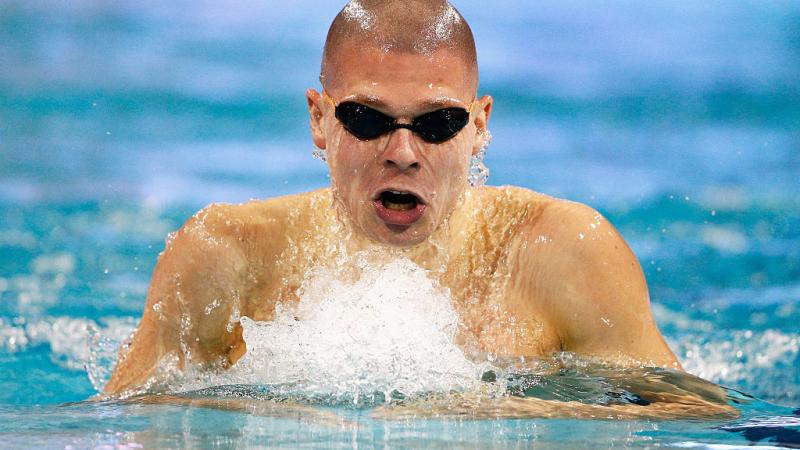 a para swimmer comes out of the water to take a breath