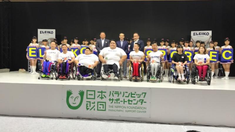 a Para powerlifter on a stage surrounded by young children