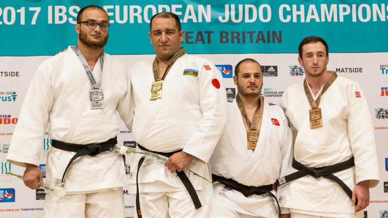 Azerbaijan judo team four male judoka stand on a podium