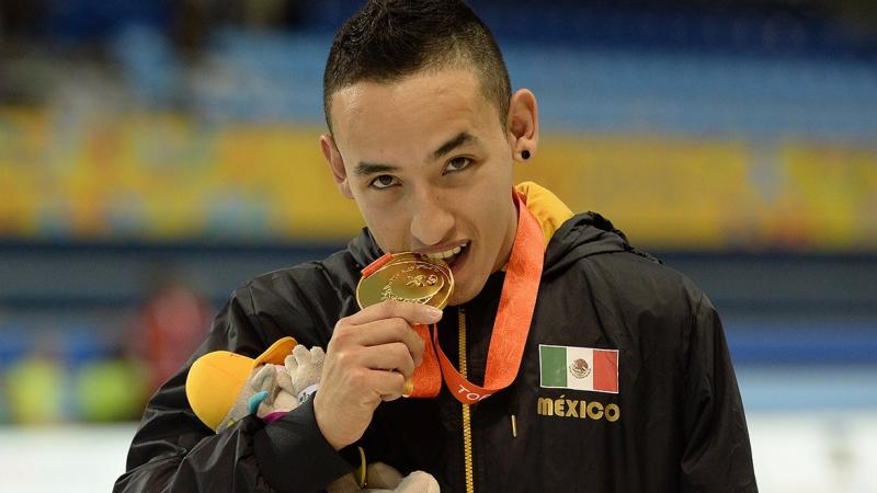 a man bites his medal on the podium