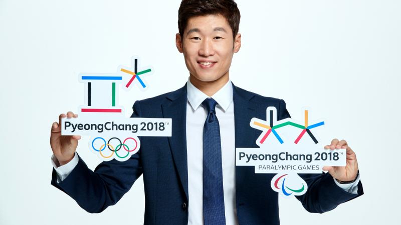 A man poses with the Olympic and Paralympic logos for PyeongChang 2018