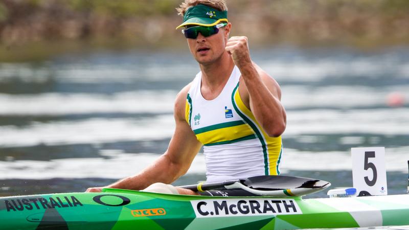 Man in canoe pumps his fist after winning