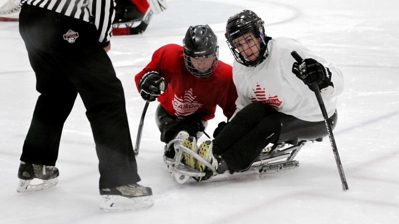 two female Para ice hockey players are given instructions on the ice