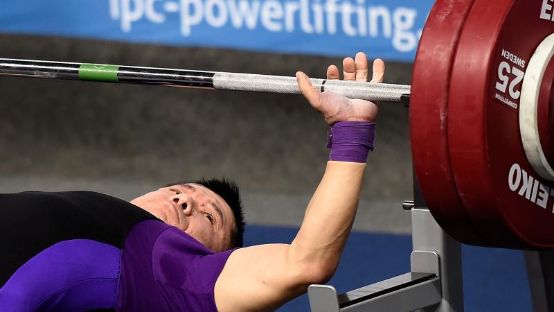 Man lays on bench preparing to bench press. 