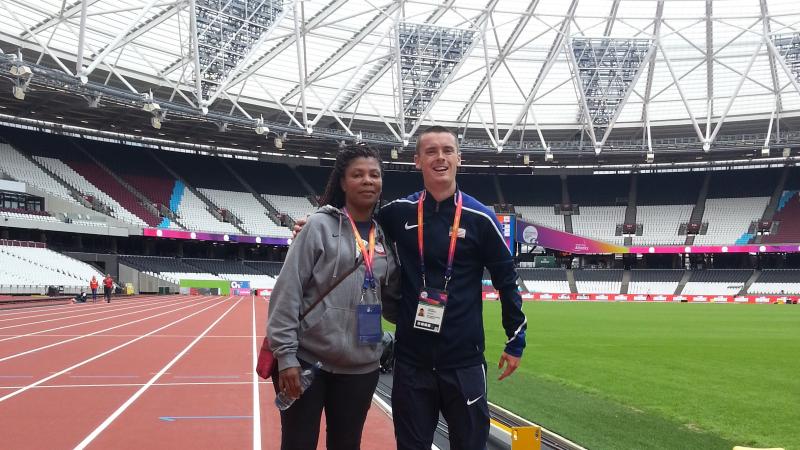 a female coach and male athlete stand together on the track at the London Stadium