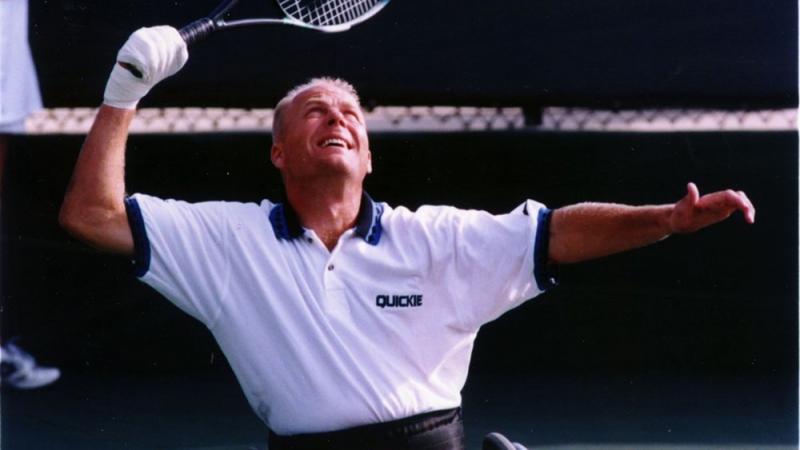 a male wheelchair tennis player takes a shot