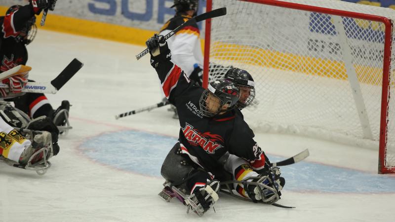 a Para ice hockey player raises his arm in celebration at a goal