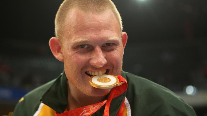 a male Para athlete bites his medal