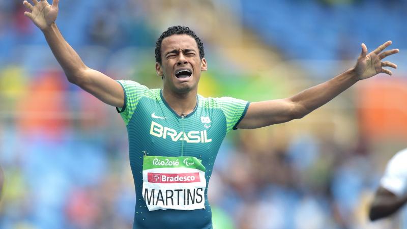 a Para athlete cries out in celebration as he crosses the finish line