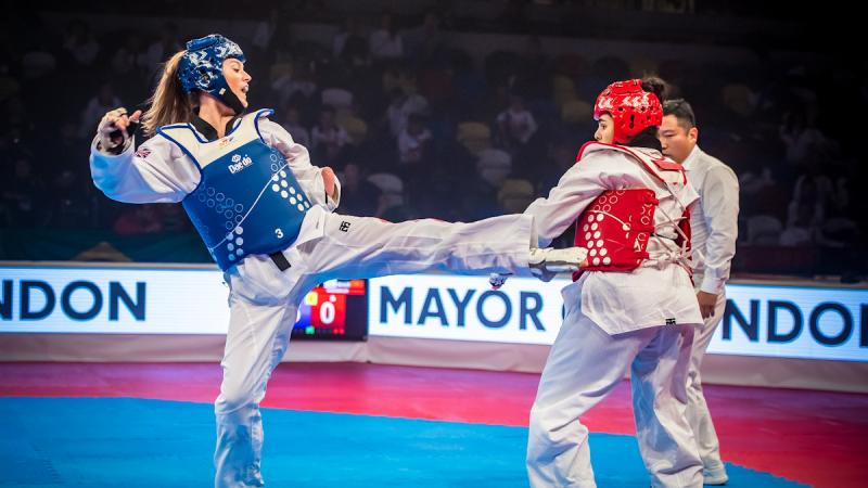 two female Para taekwondo fighters kick at each other
