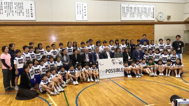 Children from the Akasaka Elementary School pose for picture in a goalball court with representatives from the IPC, NPC Japan and Nippon Foundation