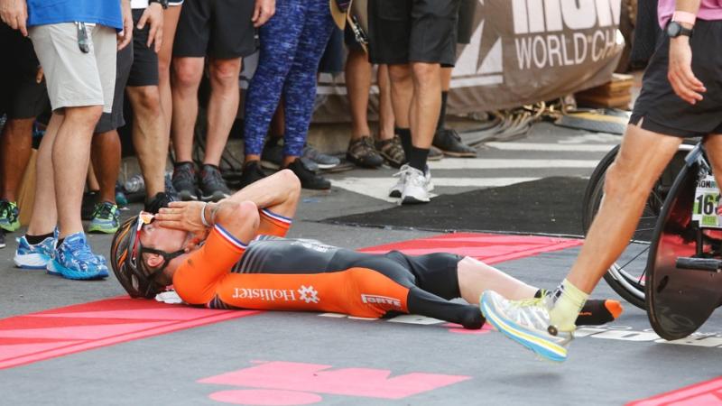 a man lies on the road celebrating after crossing the finish line