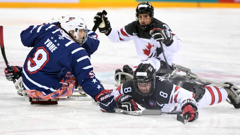 Para ice hockey players contest a puck