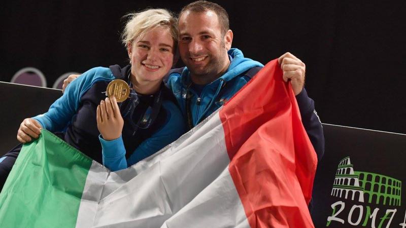 a man a woman smiling with a gold medal and the Italian flag