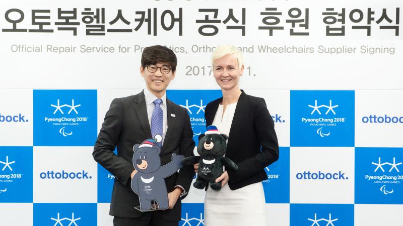 a man and a woman standing holding mascots