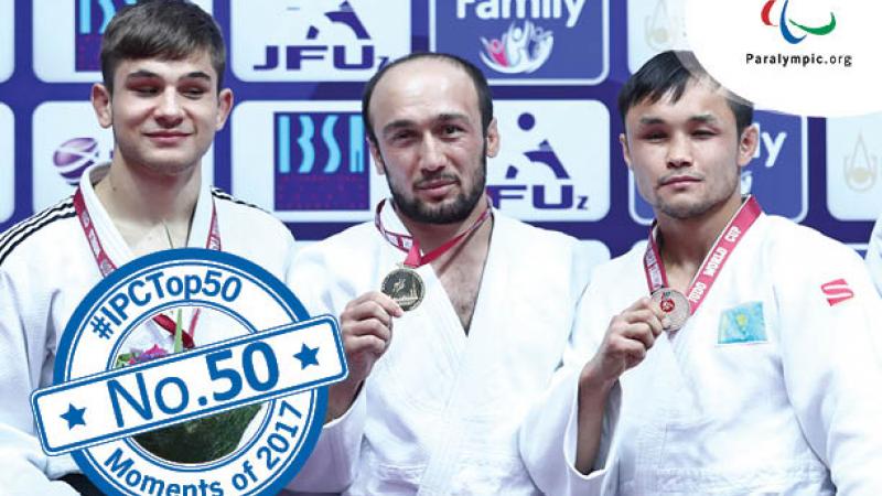 a group of four judokas stand smiling on the podium