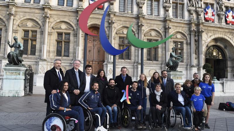 Group of people smiling in front of the Agitos logo and the municipality of Paris