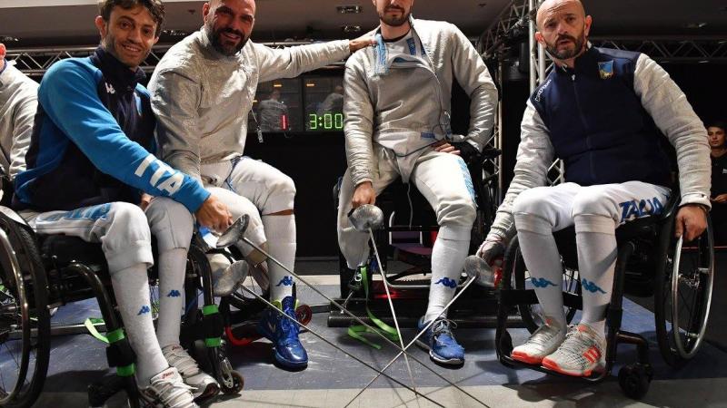 Four male wheelchair fencers pose with their swords 