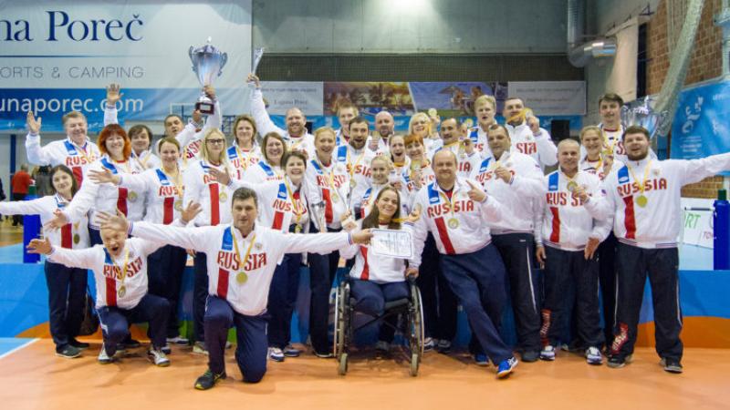 a group of male and female sitting volleyball players celebrate