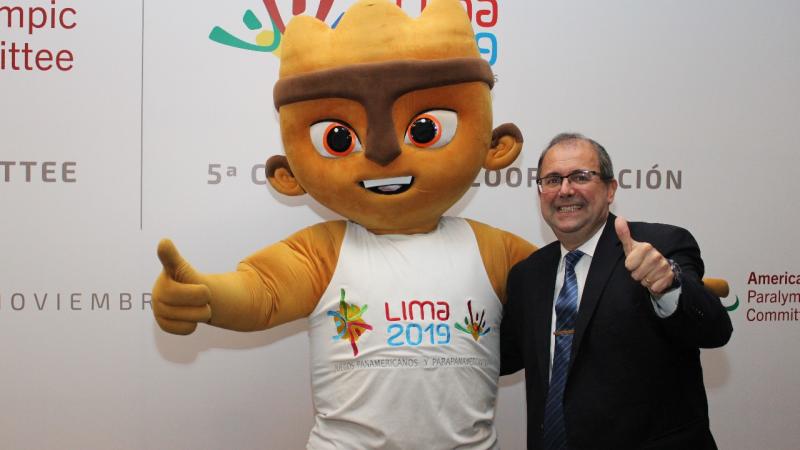 A cuddly mascot and a man give a thumbs up to the camera
