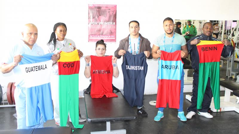 a group of Para powerlifters hold up their lifting suits