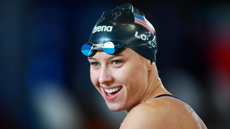 a female Para swimmer smiles after winning her race