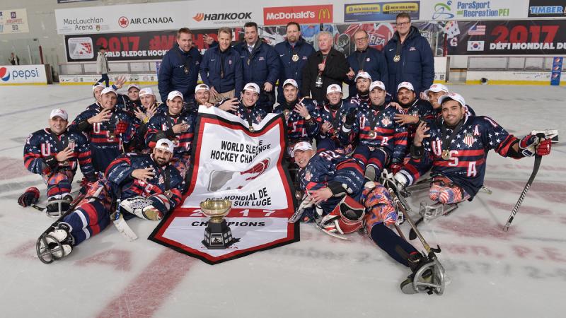 A group of Para ice hockey players pose with their trophy on the ice